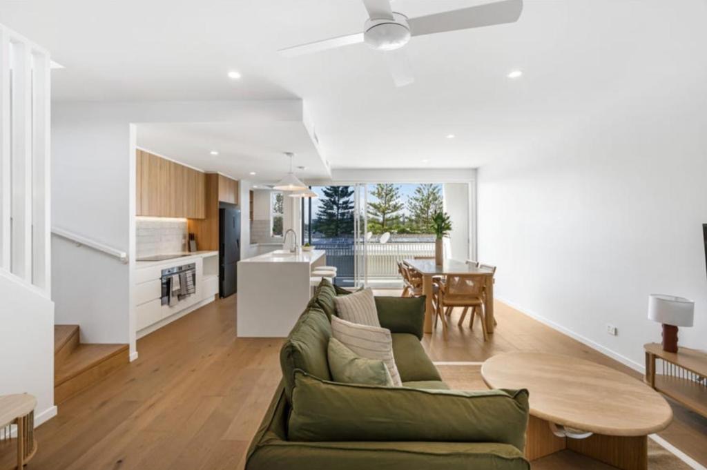 Arvia Villa Koala Park living room with green sofa, kitchen and balcony